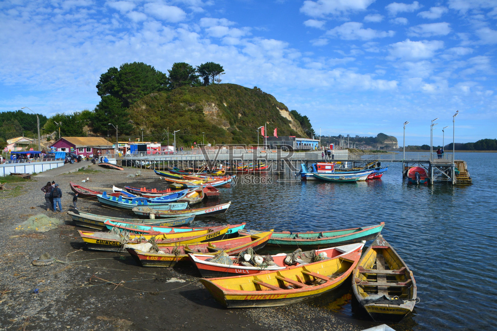 阳光明媚的日子里，海边停靠着五颜六色的小船照片摄影图片
