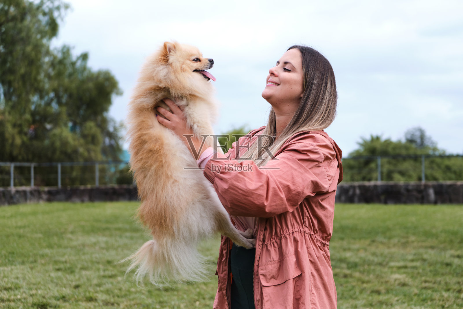 一个女孩在公园里和她的博美犬玩耍。照片摄影图片