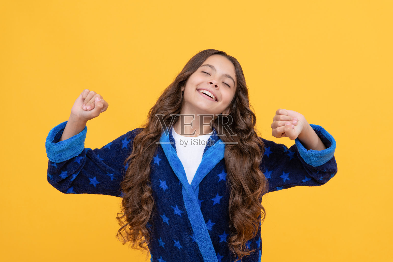 快乐的少女伸展。睡眼惺忪的孩子穿着睡衣。微笑的孩子穿着柔软的睡衣。照片摄影图片