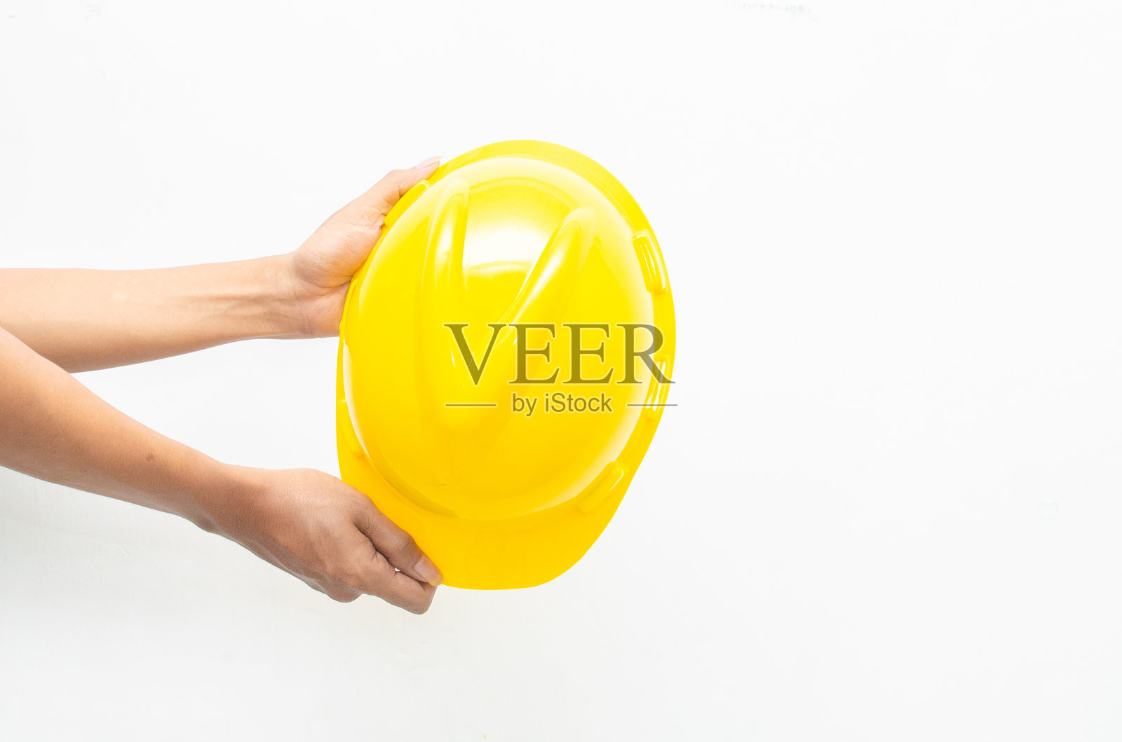 男性手拿黄色安全安全帽孤立在白色背景。安全生产理念。劳动节概念。照片摄影图片