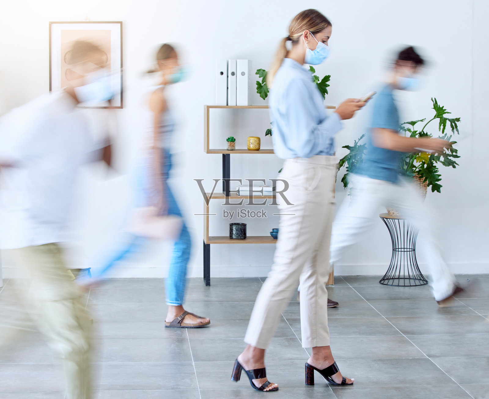 新冠肺炎，忙碌的办公室，戴着口罩在现代办公室里打电话的女人。动态模糊、快速商务人士和冠状病毒工作场所，员工在智能手机上移动、工作和打字照片摄影图片