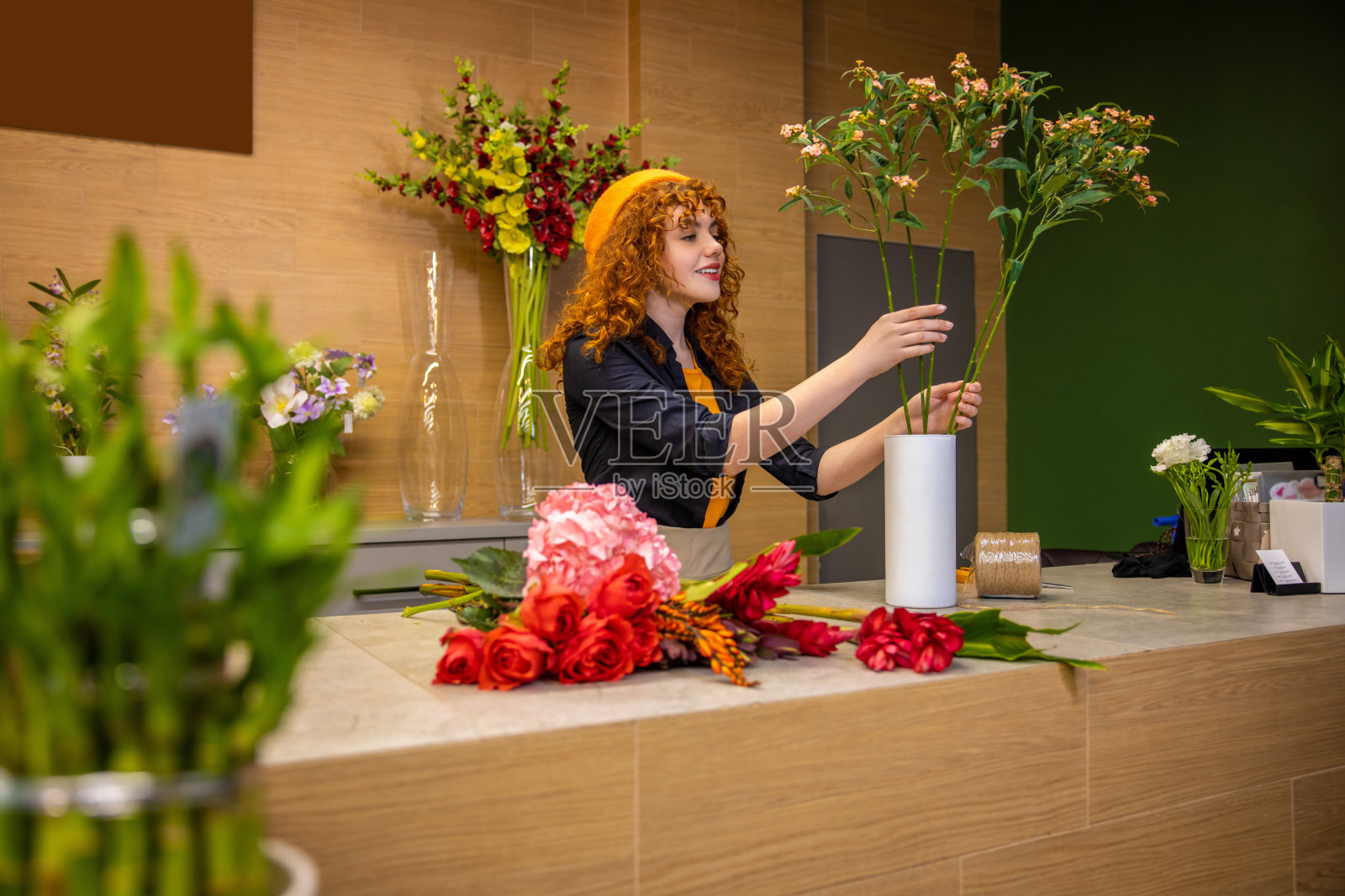 生姜女孩整理鲜花，看起来很满足照片摄影图片