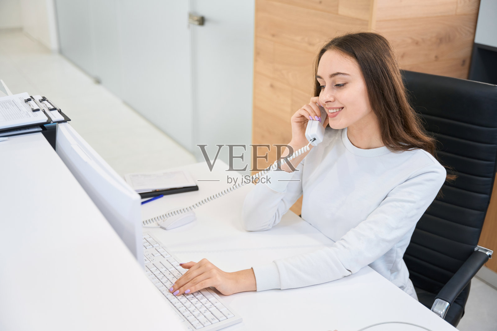 开朗的秘书在前台打电话照片摄影图片