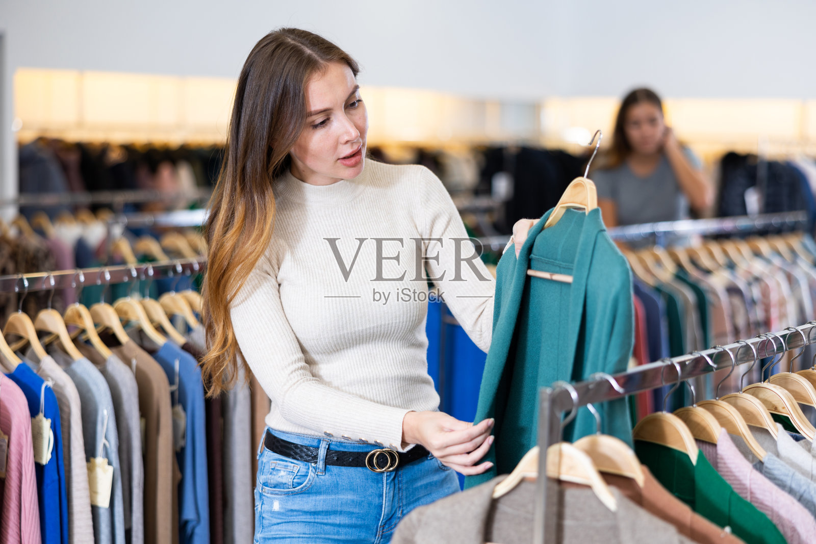 年轻女子选择温暖的开衫在商店照片摄影图片