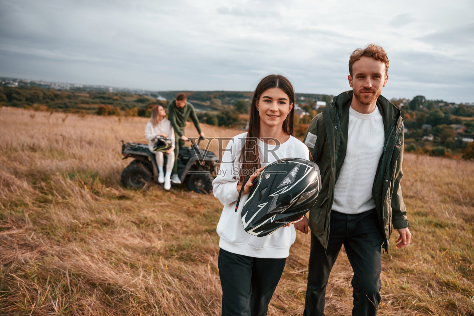 边走边笑。可爱的年轻夫妇骑着四轮自行车在户外的田野上照片摄影图片