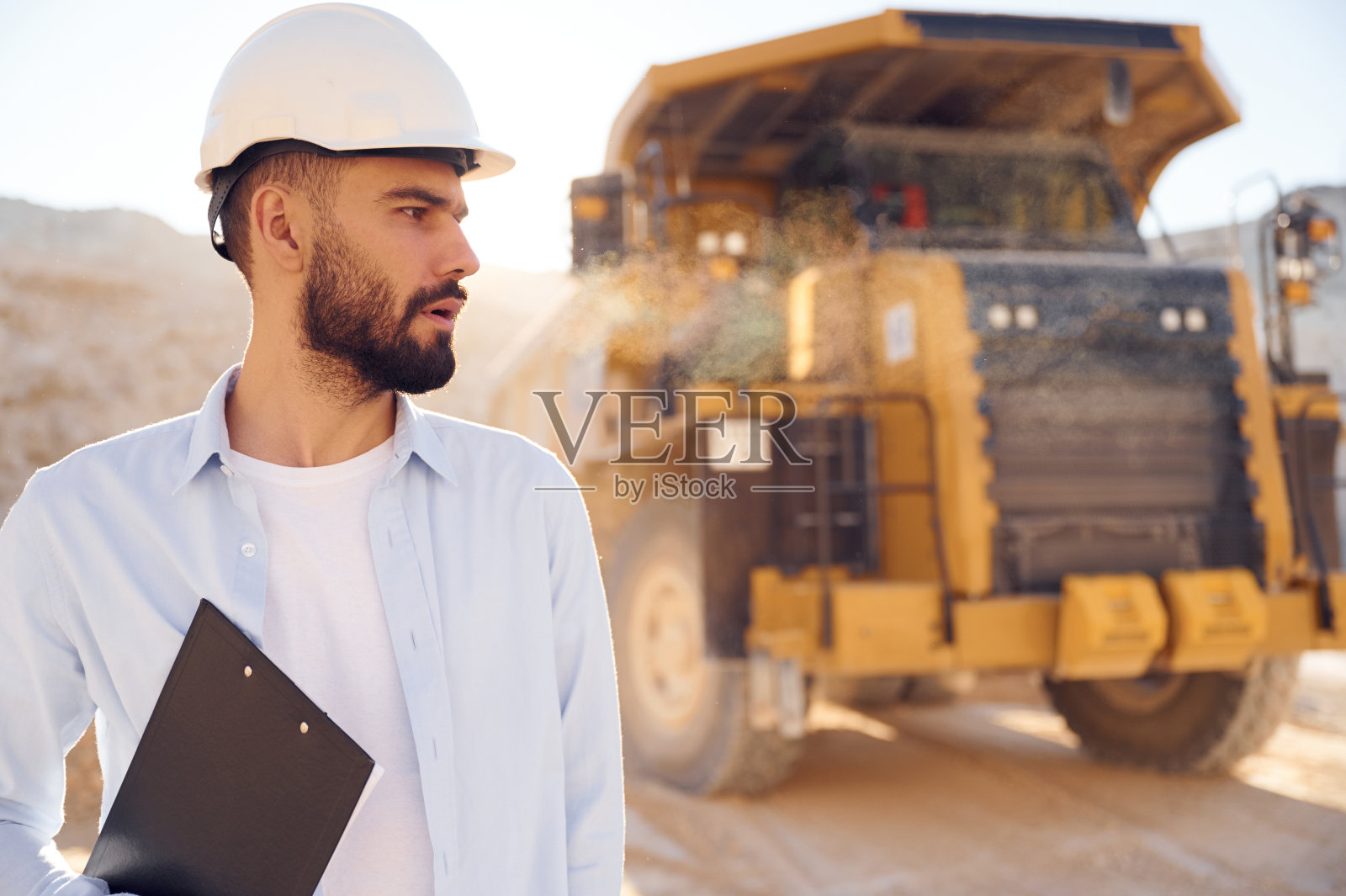 穿着制服的漂亮男人白天在采石场工作。有拖车照片摄影图片