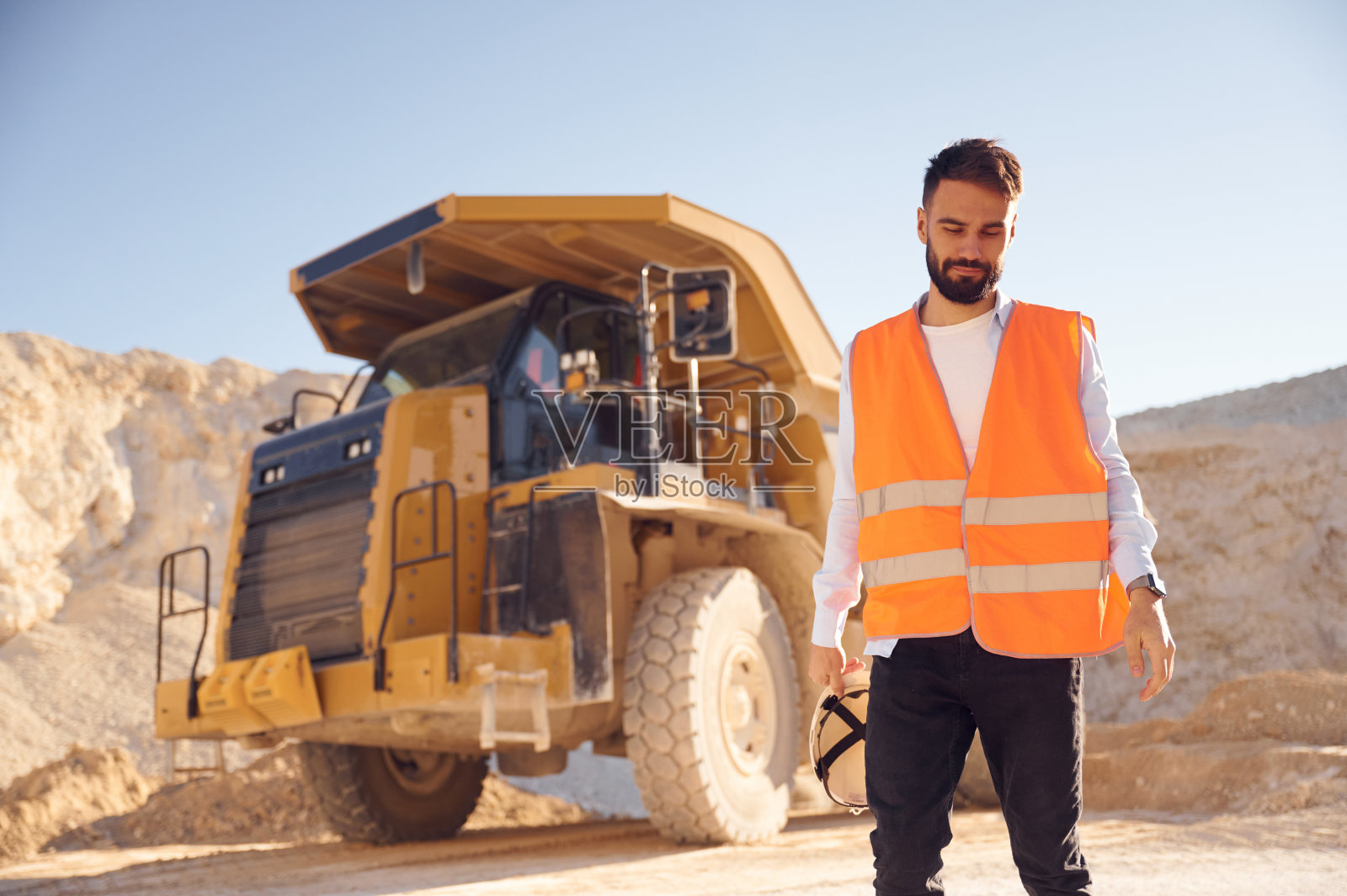 感觉累了。站在拖车旁边。穿制服的人白天在采石场工作照片摄影图片