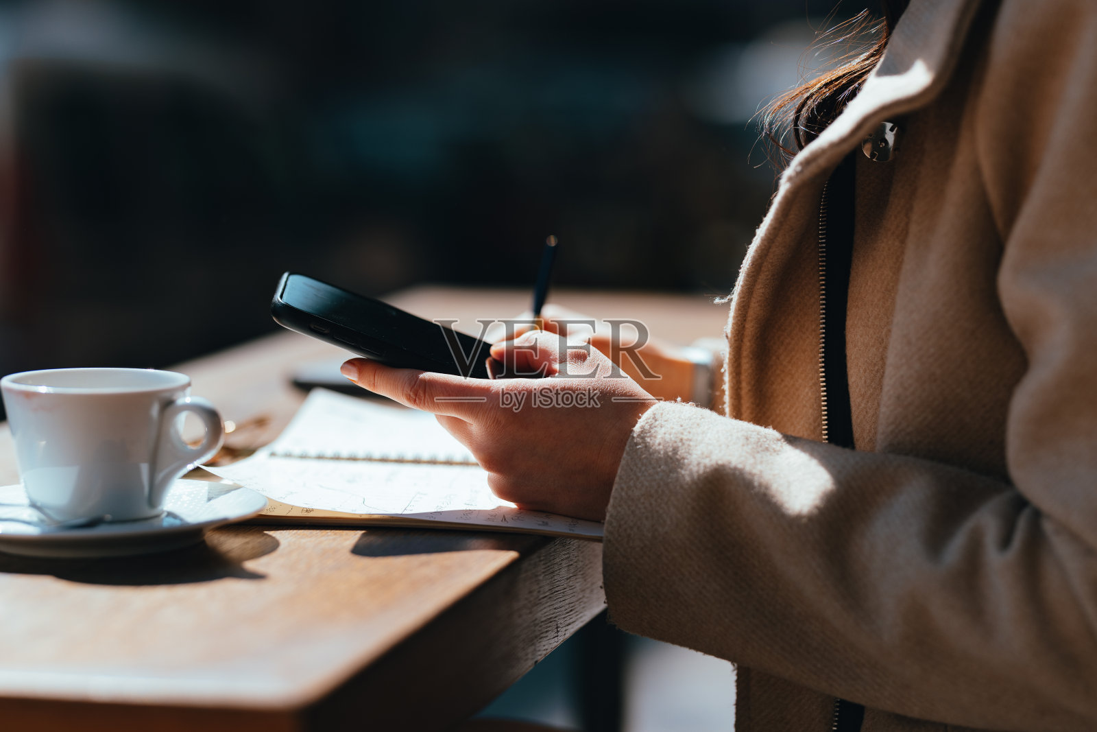 匿名女子坐在咖啡店里拿着智能手机打字(复印空间)照片摄影图片