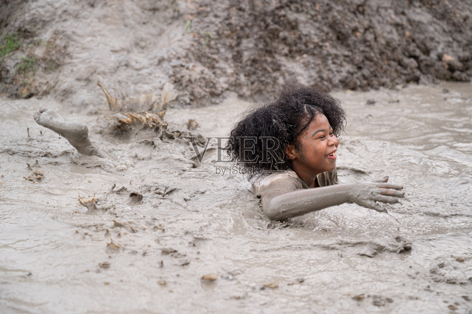 有趣的非裔美国女孩在泥坑里玩照片摄影图片