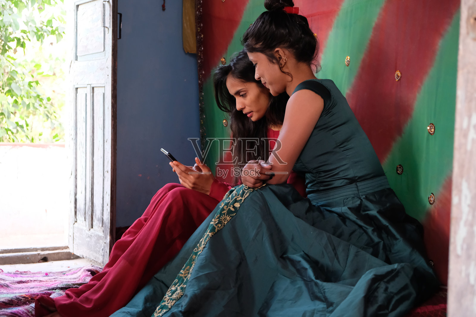 特写镜头是两位穿着传统服饰的南亚女性朋友一起看手机照片摄影图片