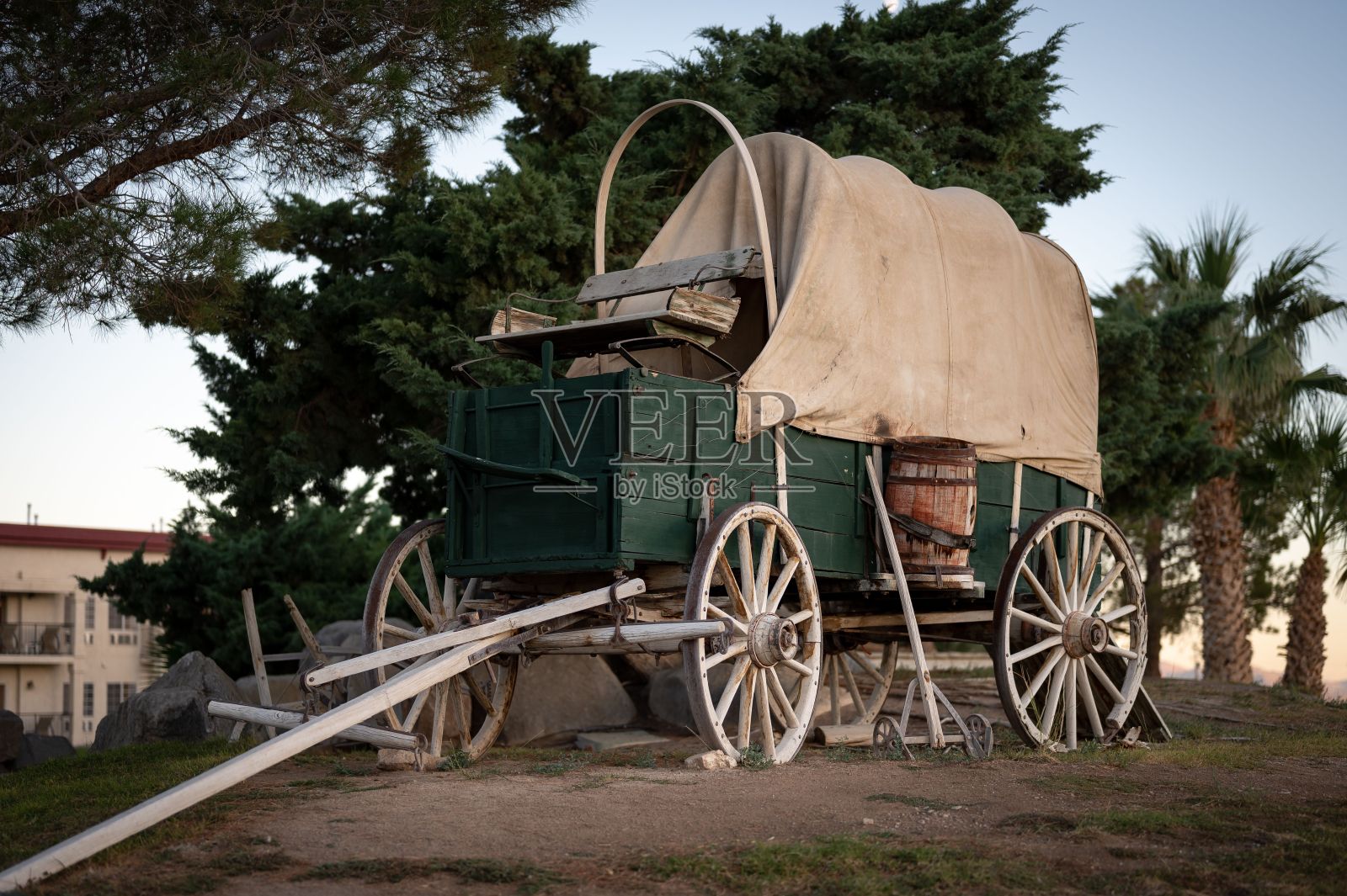 一辆带有帆布屋顶的旧木制马车的细节。它是绿色的，旁边是一个马厩照片摄影图片