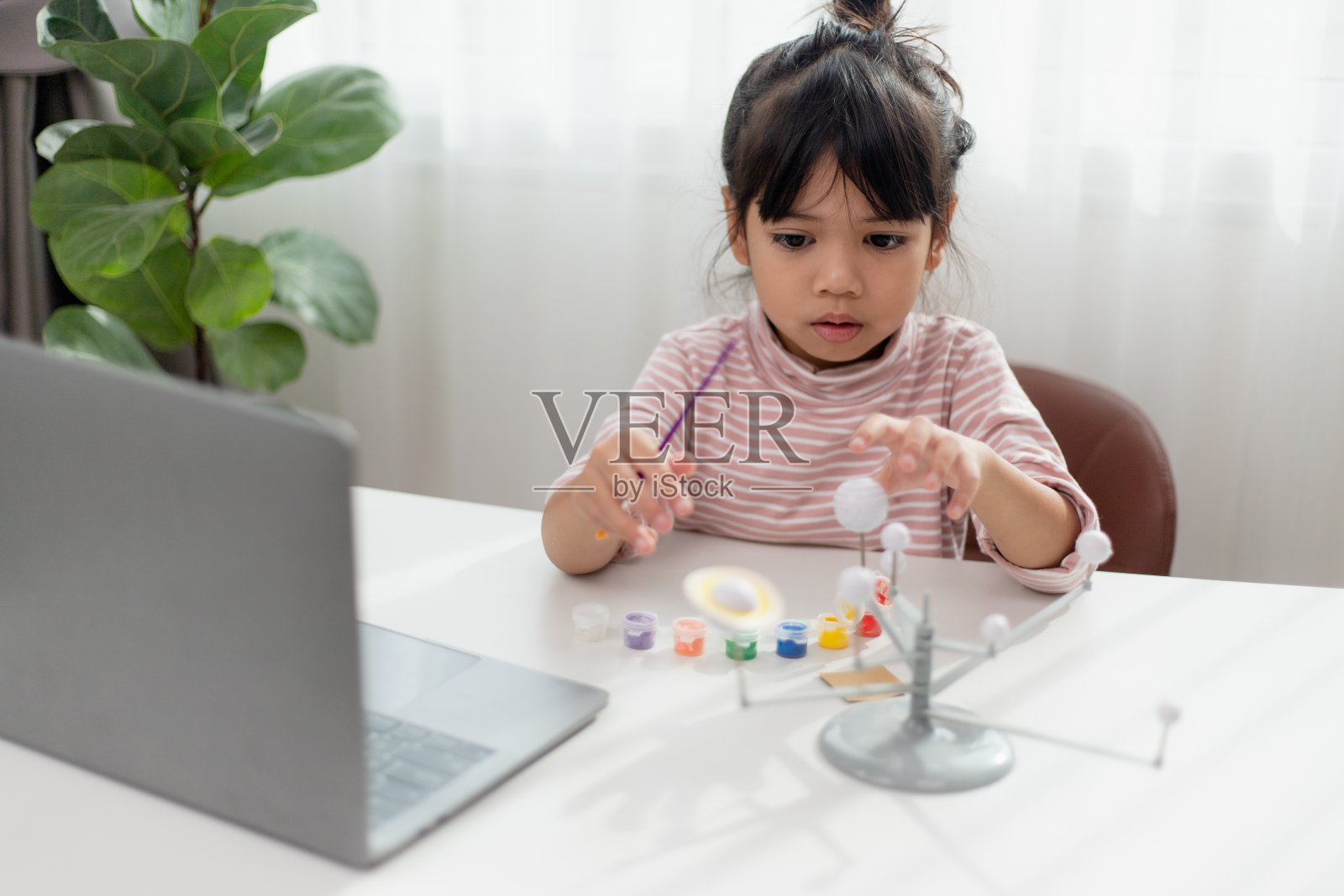 亚洲小女孩在地理课上研究太阳系。看看行星的比例模型照片摄影图片