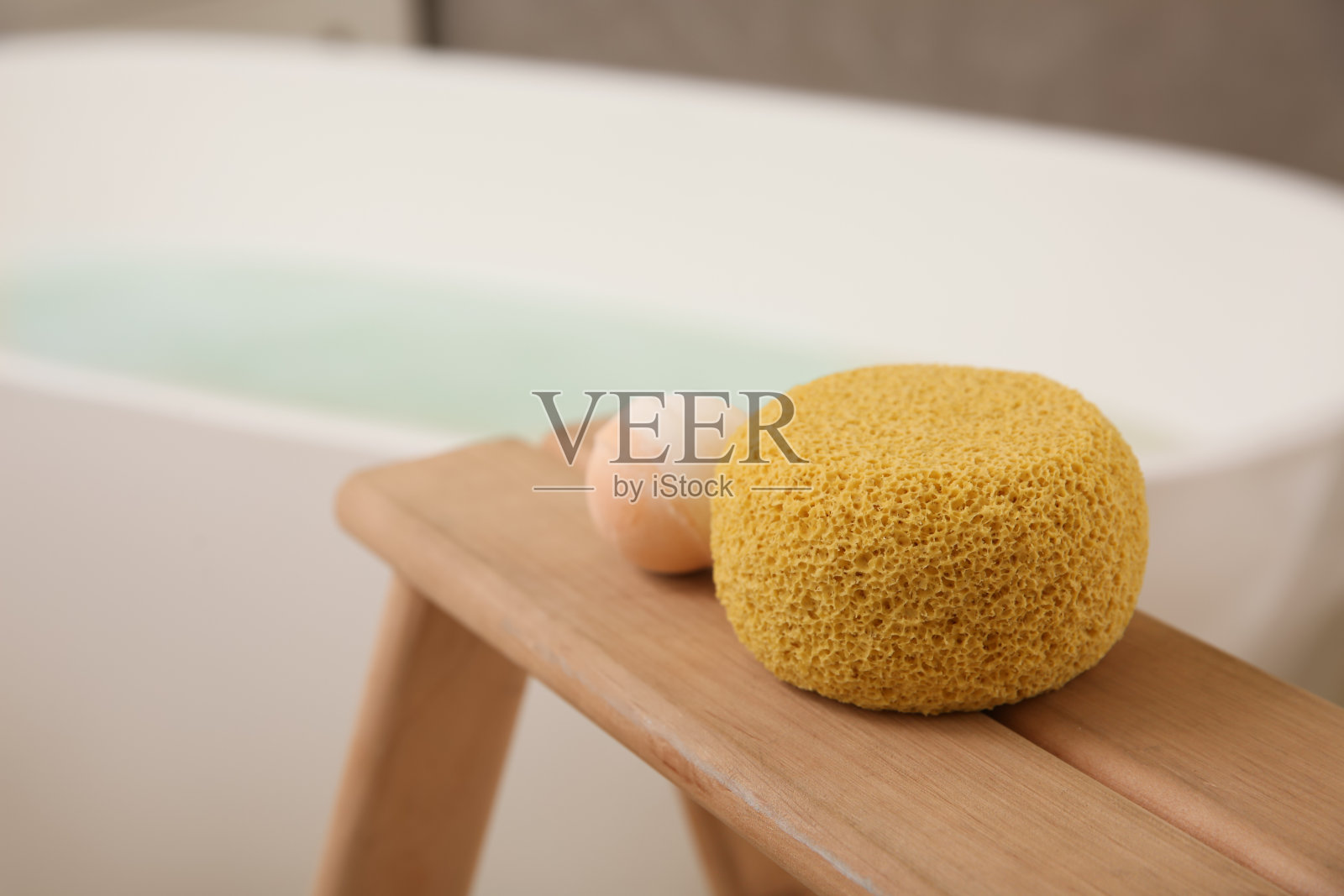 在室内浴缸附近的木架上放置海绵和浴弹照片摄影图片