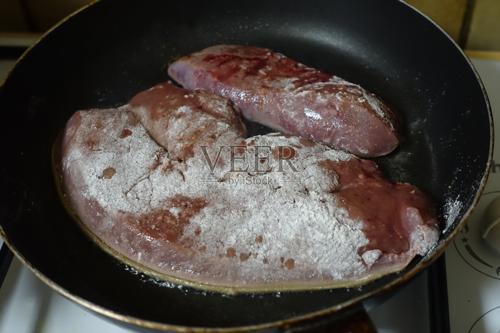 在煎锅里煎的撒了面粉的小牛肉肝照片摄影图片