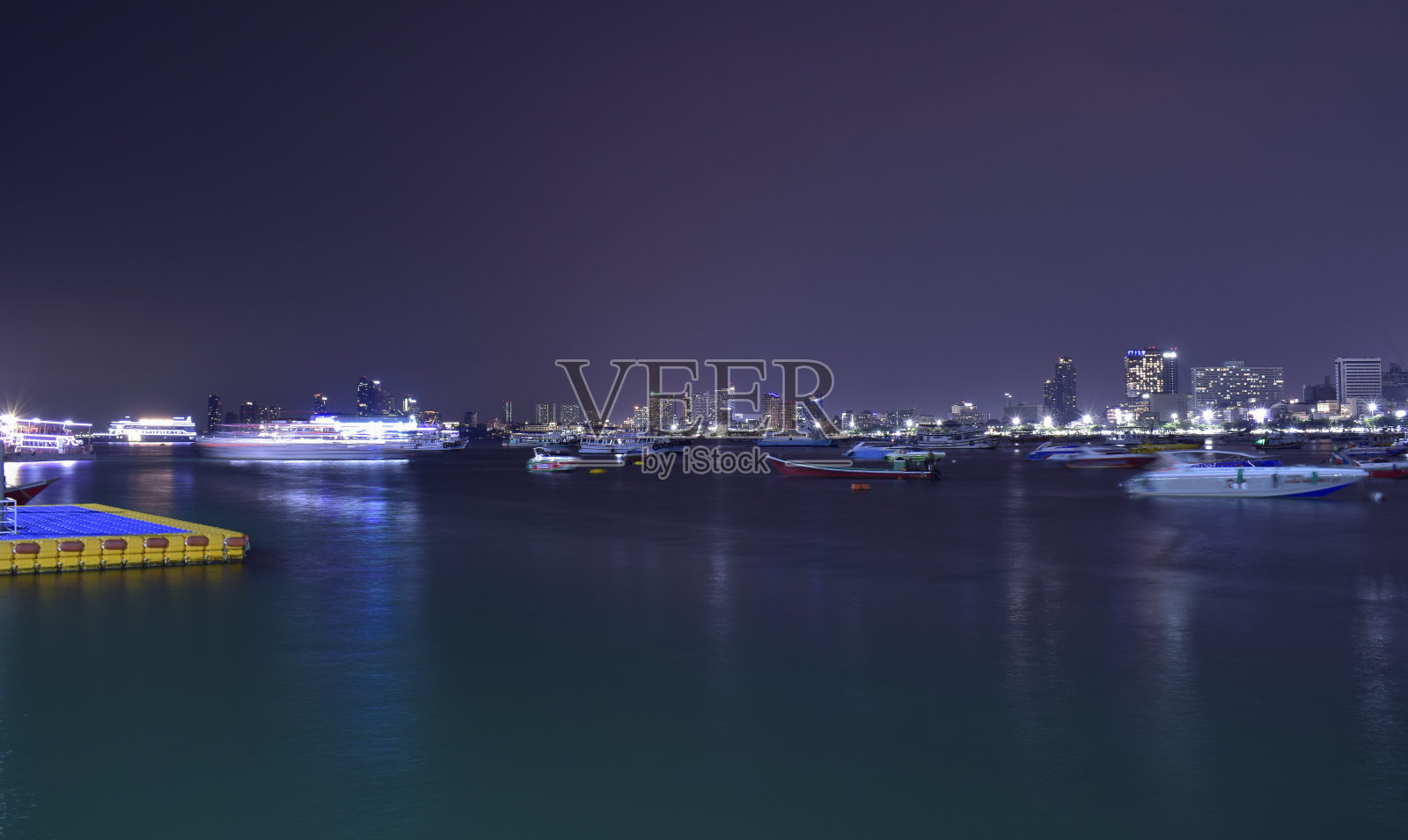 晚上，五彩缤纷的灯光映在海面上。照片摄影图片