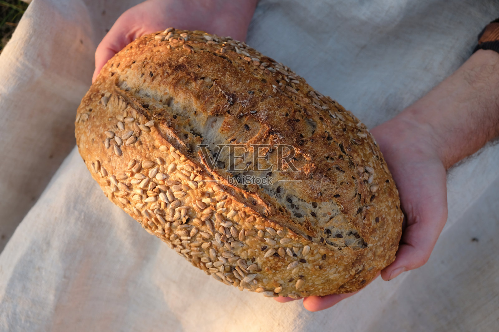 男人手里拿着葵花籽面包。晚上的黄金时间。前视图。照片摄影图片