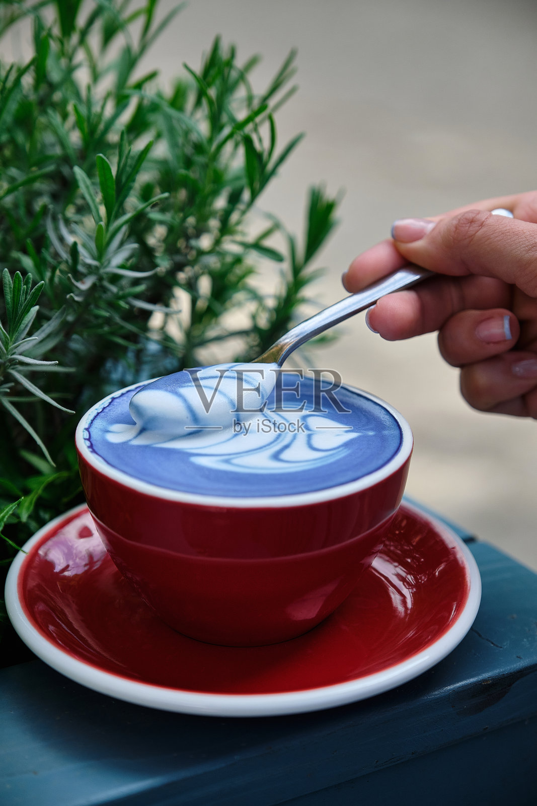 女孩用茶匙收集蓝色抹茶的泡沫照片摄影图片