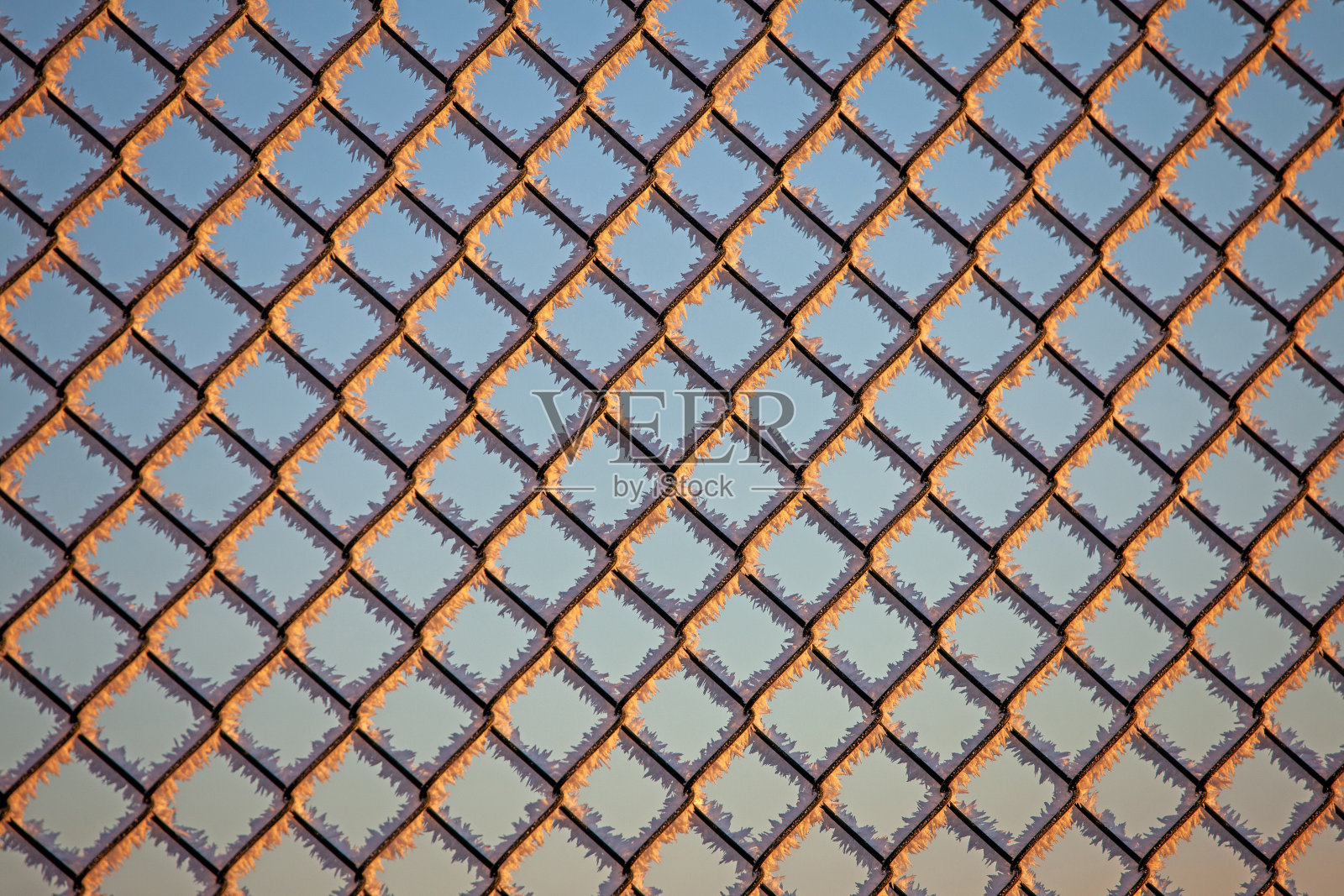 冬天的金属栅栏上覆盖着冰晶和阳光照片摄影图片