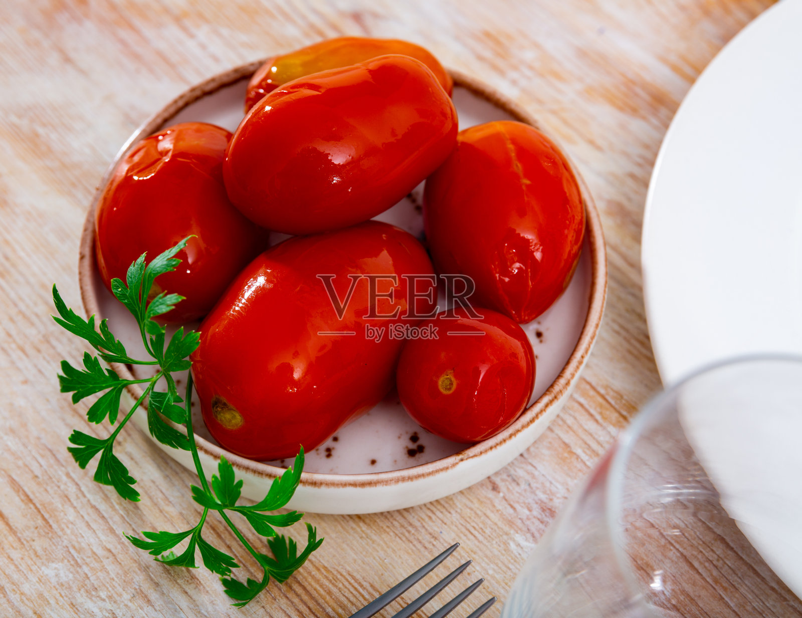 多汁的腌制西红柿盛在装饰有欧芹的盘子上。自制的罐头。泡菜照片摄影图片