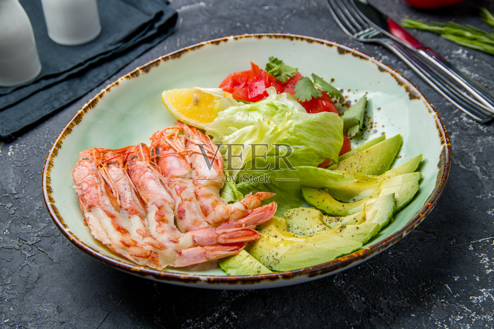 灰色的水泥桌子上放着一盘海鳌虾和牛油果照片摄影图片