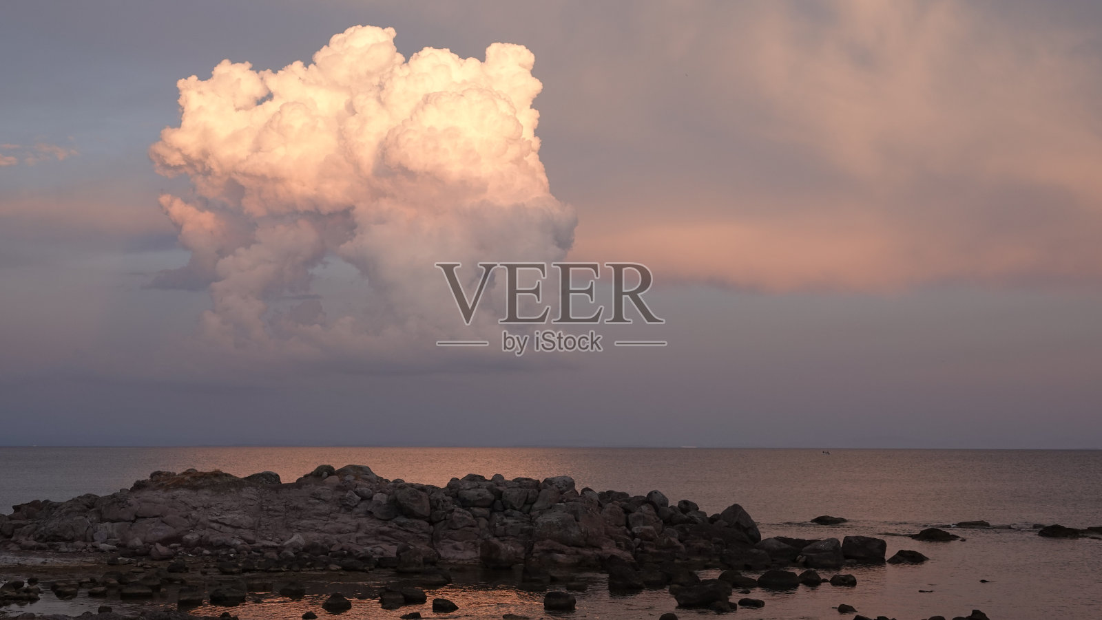 海面上的一大片白云，在日落时呈现出银色、浅蓝色和橙色的阴影照片摄影图片