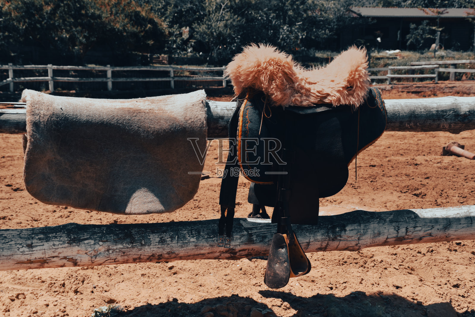 传统的马鞍和马术装备立在马场的白色栅栏上照片摄影图片
