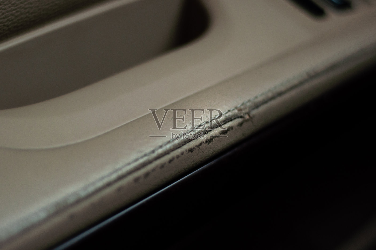 那辆车的驾驶座的扶手用米色皮革包裹着。破旧的皮革内饰。照片摄影图片