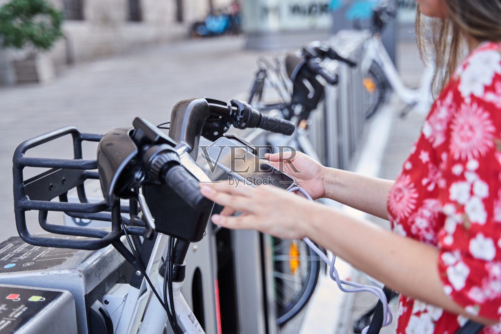 年轻时尚女性使用自行车租赁手机应用的特写，拉丁女性浏览智能手机站在共享单车附近骑自行车的肖像，城市健康生活方式的概念照片摄影图片