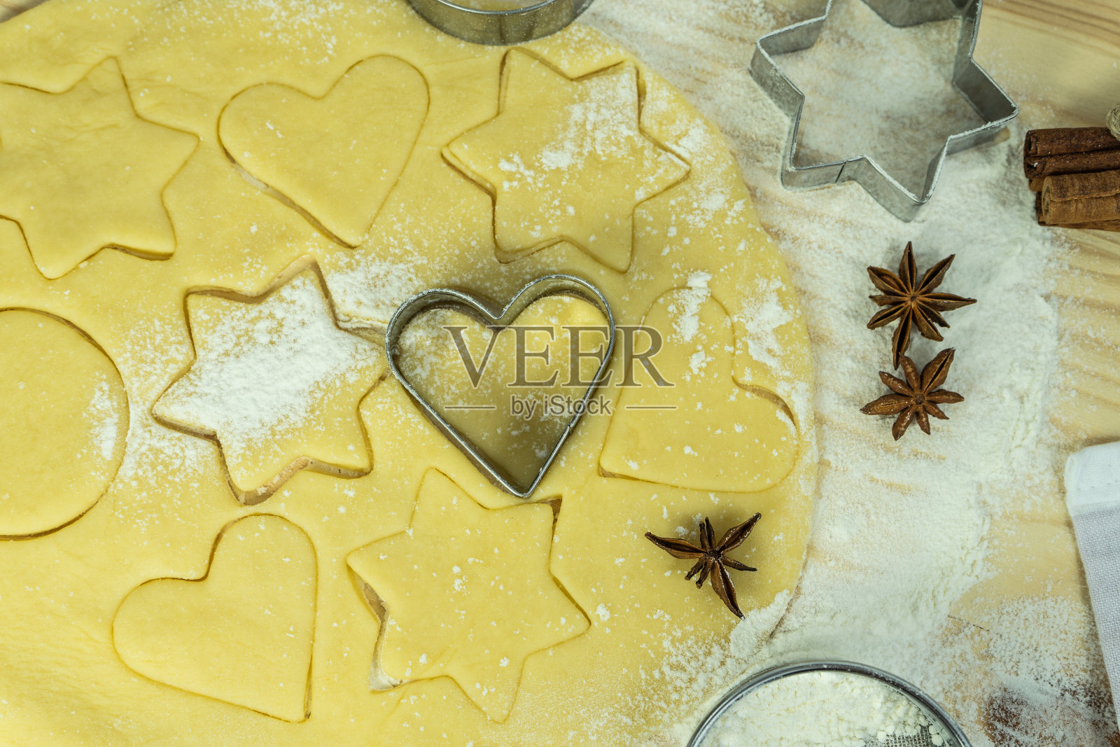 我们用手把心形饼干刀压进面团里。用心形饼干切刀、各种食材和器皿烘焙的装饰。照片摄影图片