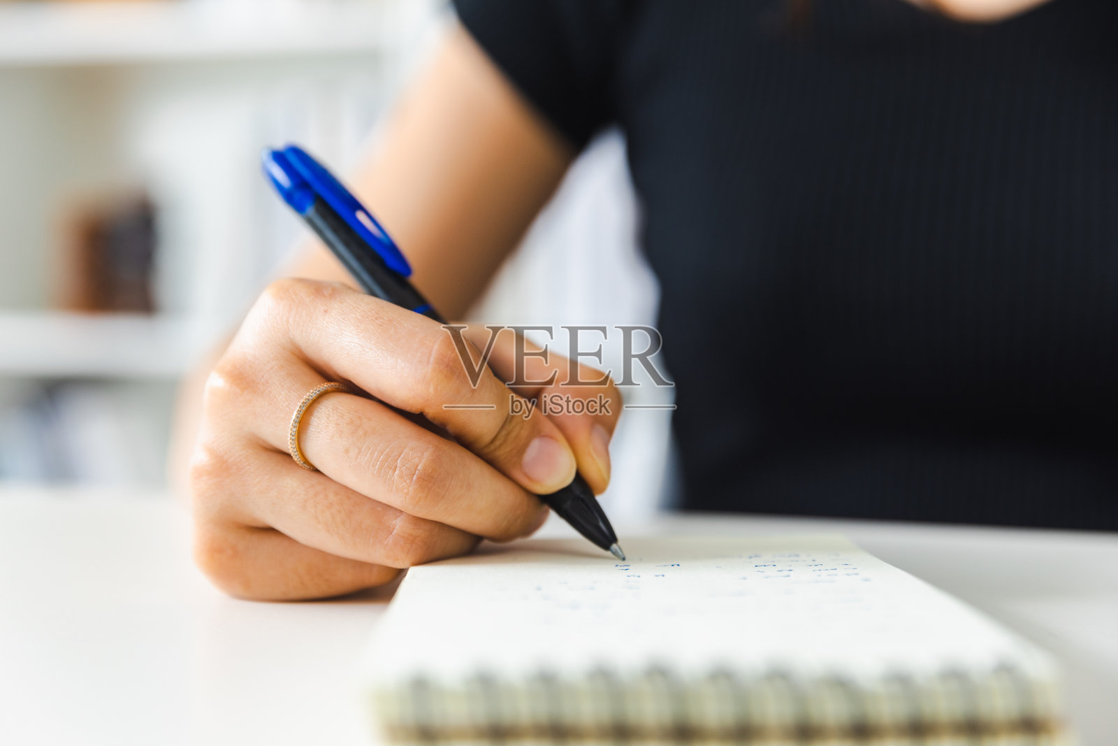 用笔在记事本上写字的人。照片摄影图片