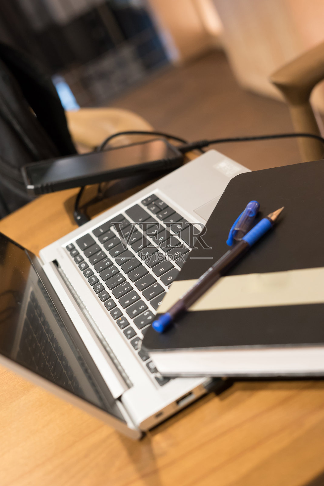 笔记本和智能手机在木桌上，铅笔在笔记本上照片摄影图片