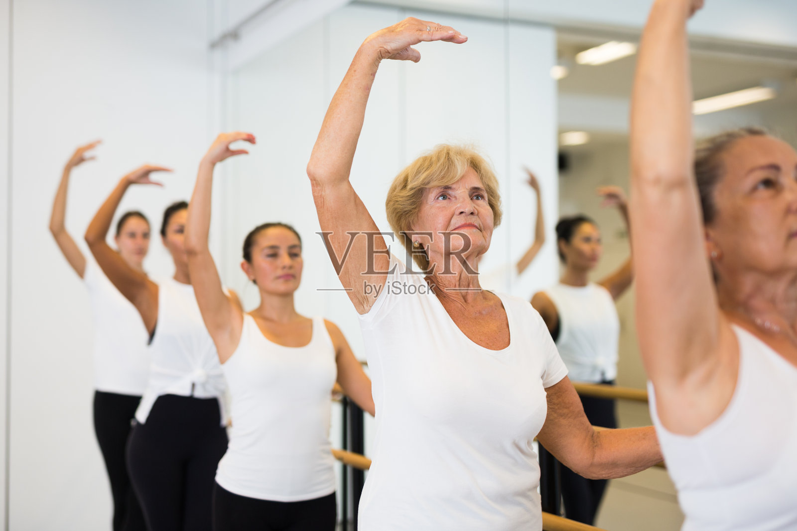 一组芭蕾舞者站在一个手杠和达到超过手在健身室照片摄影图片