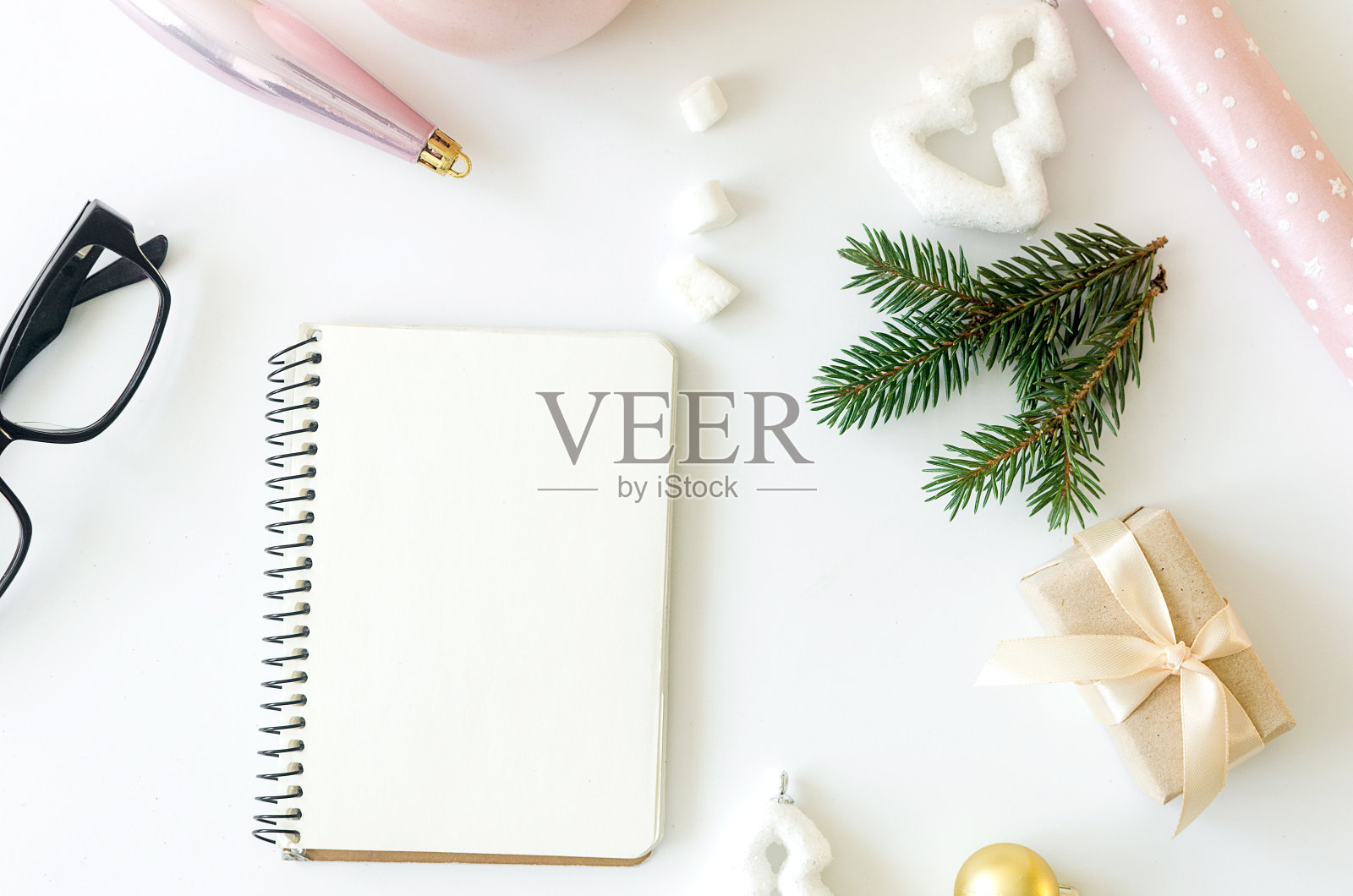 桌上放着空笔记本、眼镜和圣诞装饰品。照片摄影图片