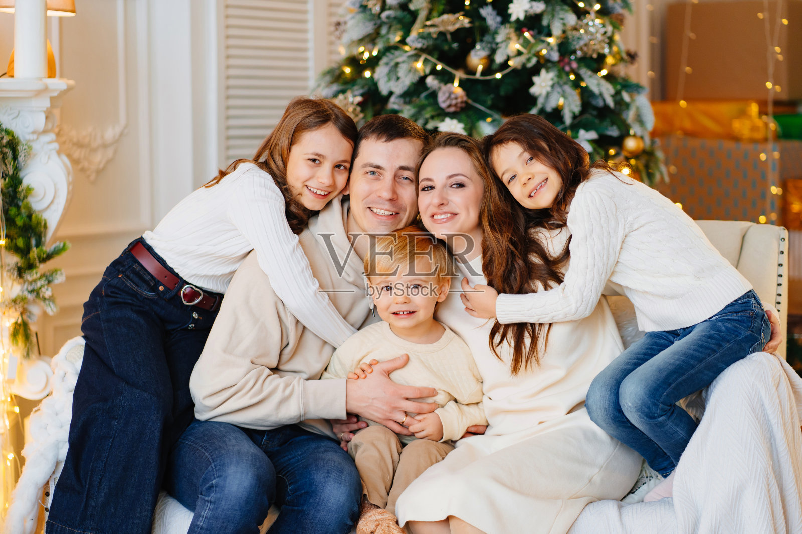 美丽幸福的大家庭坐在圣诞树旁的沙发上。照片摄影图片