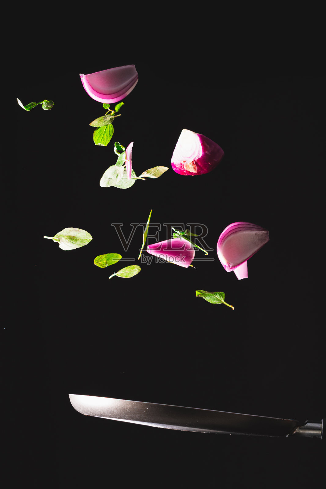 煎锅把红洋葱、奶酪、罗勒和调味料扔到空中。照片摄影图片