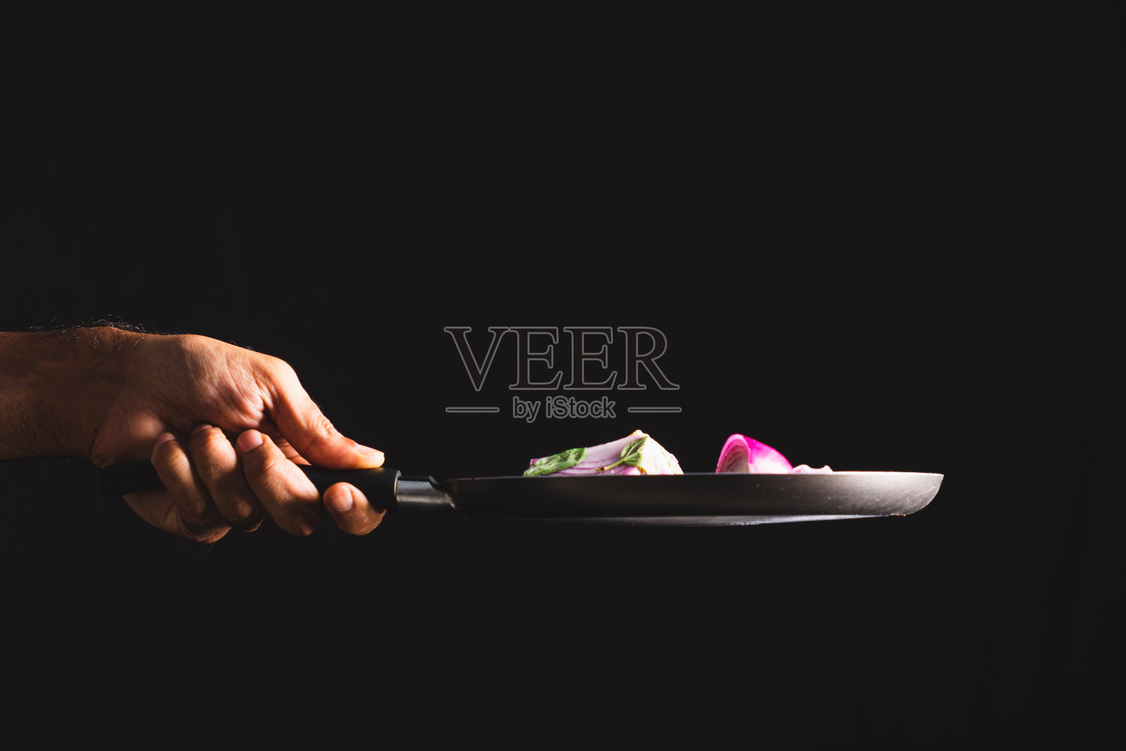 煎锅把红洋葱、奶酪、罗勒和调味料扔到空中。照片摄影图片