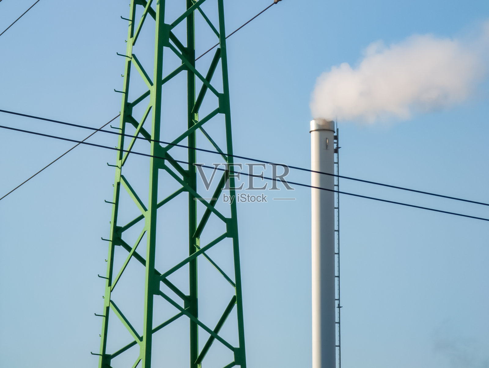 工厂烟囱冒烟。工业管道。晴天蓝天。空气污染。输电线塔照片摄影图片