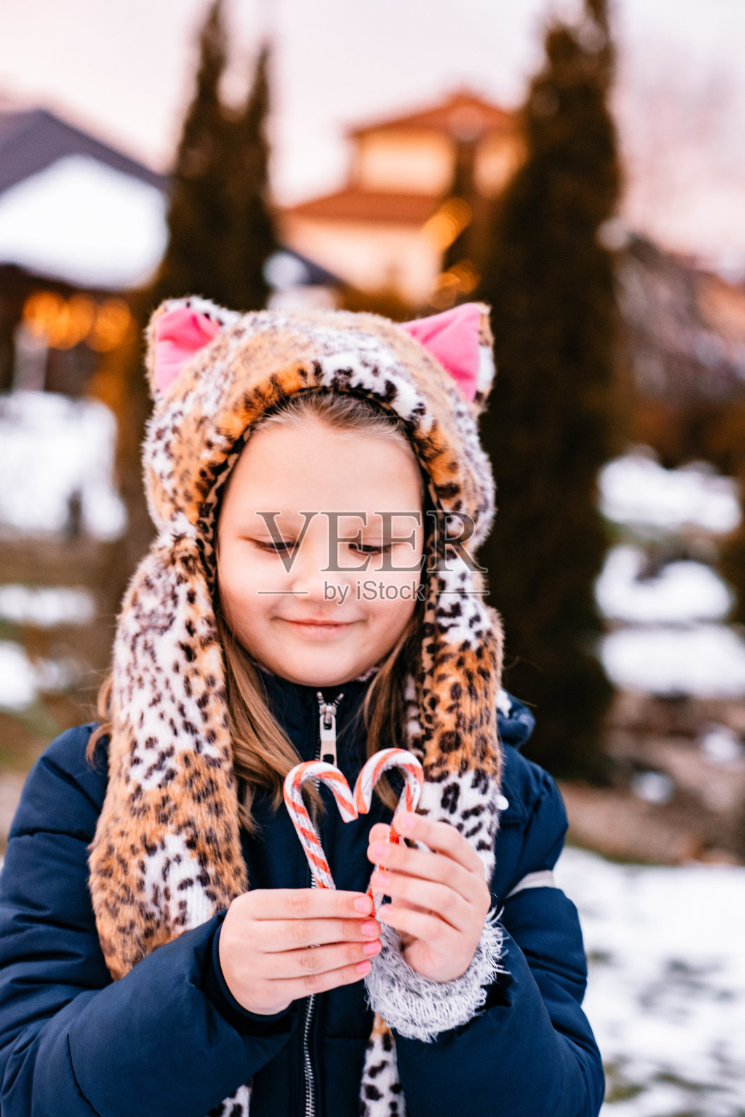一个女孩在冬天的街上，手里拿着一颗心，冬天的乐趣。照片摄影图片