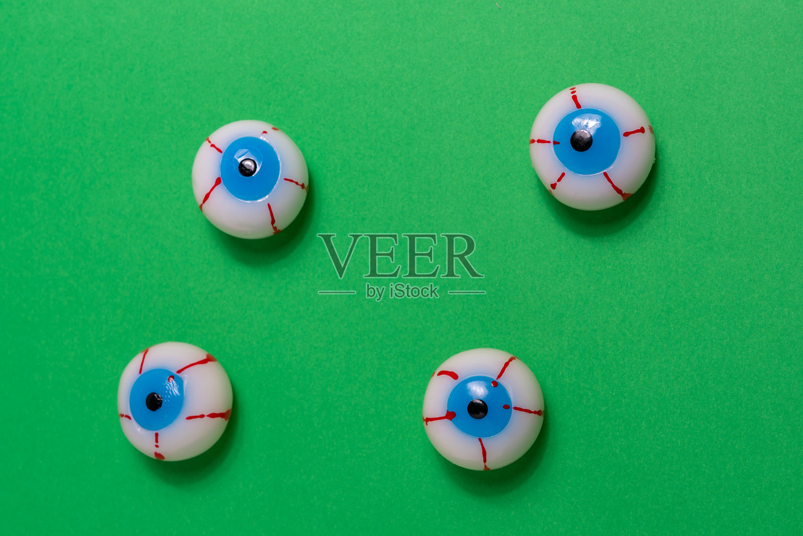 创意的布局与色彩鲜艳的血色眼球在生动的绿色背景。简约的万圣节概念。照片摄影图片