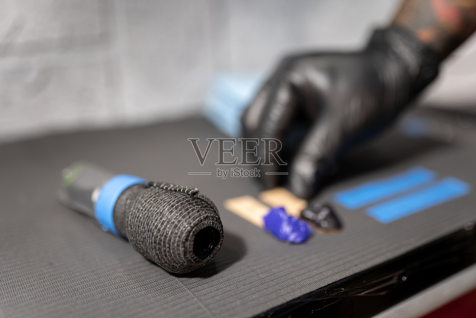 一位纹身师正在把一些凡士林留在机器旁边的工作台上照片摄影图片