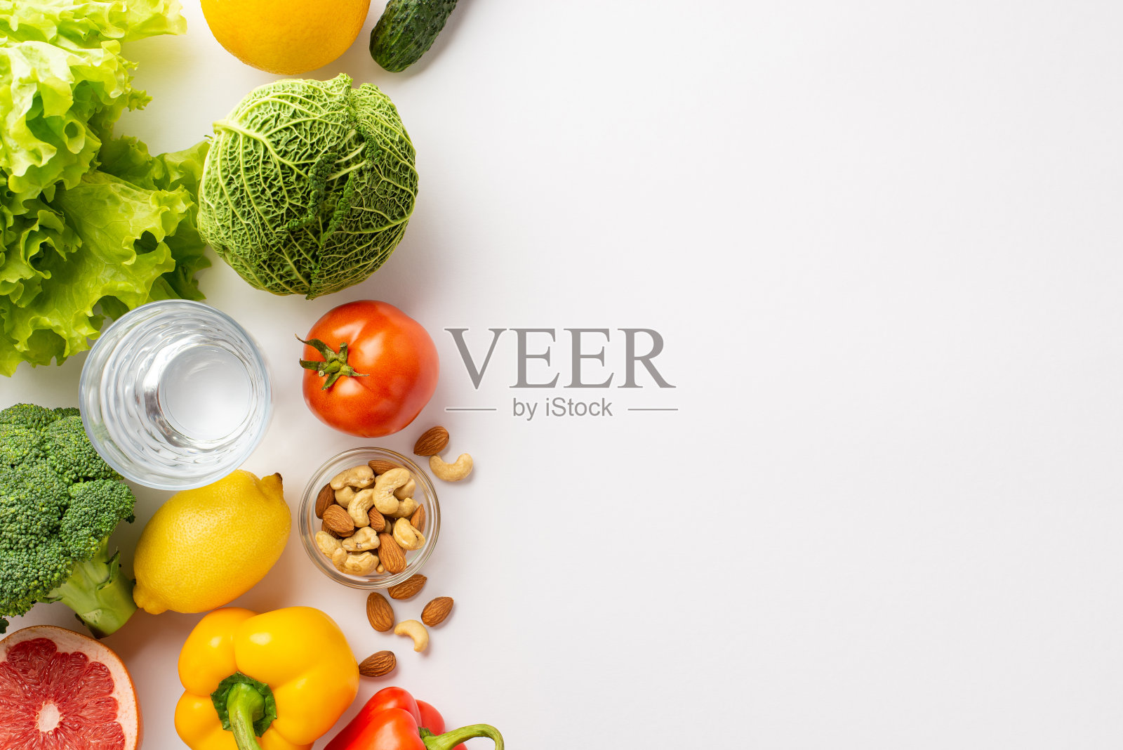 正确的营养观念。顶部视图照片的蔬菜，水果，坚果和一杯水在孤立的白色背景与空白照片摄影图片