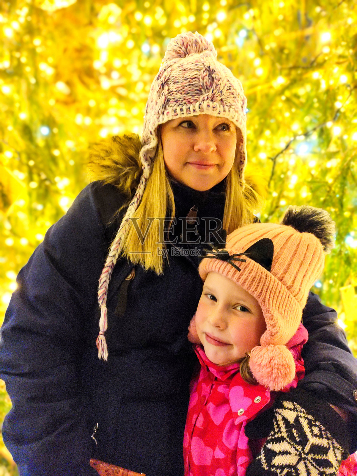 一个七岁女孩的妻子和孩子的肖像。背景是一棵戴着水钻花环的冷杉树，上面是穿着冬装的白种人一家。照片摄影图片