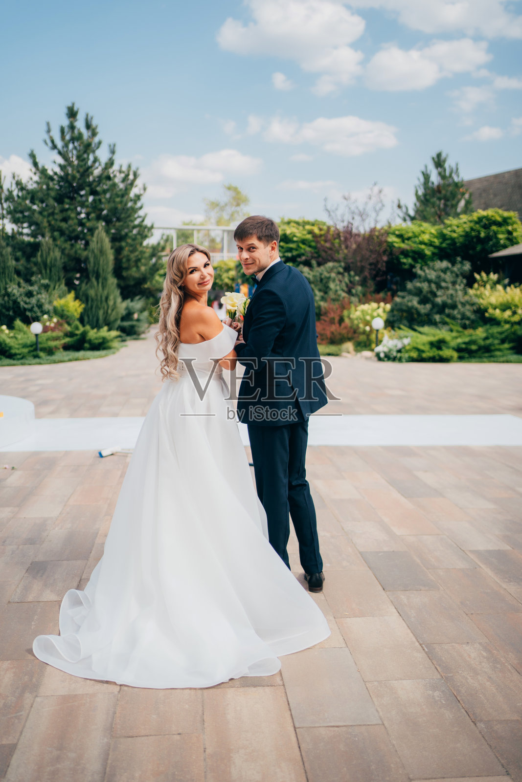 从后面看。新郎和新娘手牵着手一起走。照片摄影图片