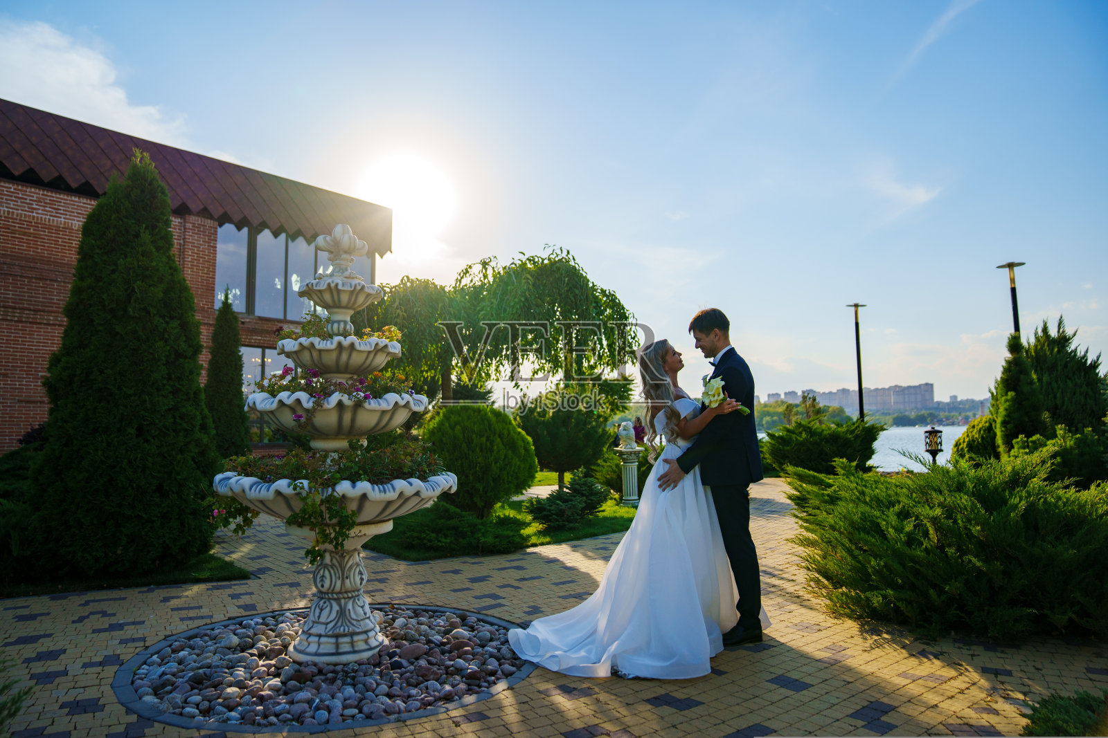 幸福的新婚夫妇。新郎和新娘在公园里穿着传统的结婚礼服。日落。照片摄影图片