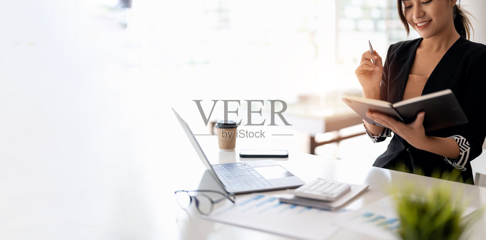 关会计的亚洲妇女手在办公室用笔在记事本上写字。企业会计概念。照片摄影图片