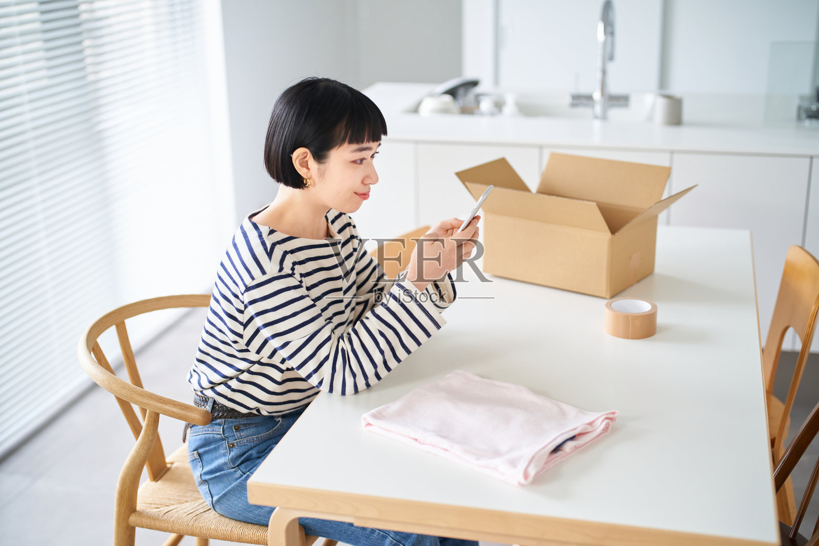 年轻女子用智能手机卖衣服照片摄影图片