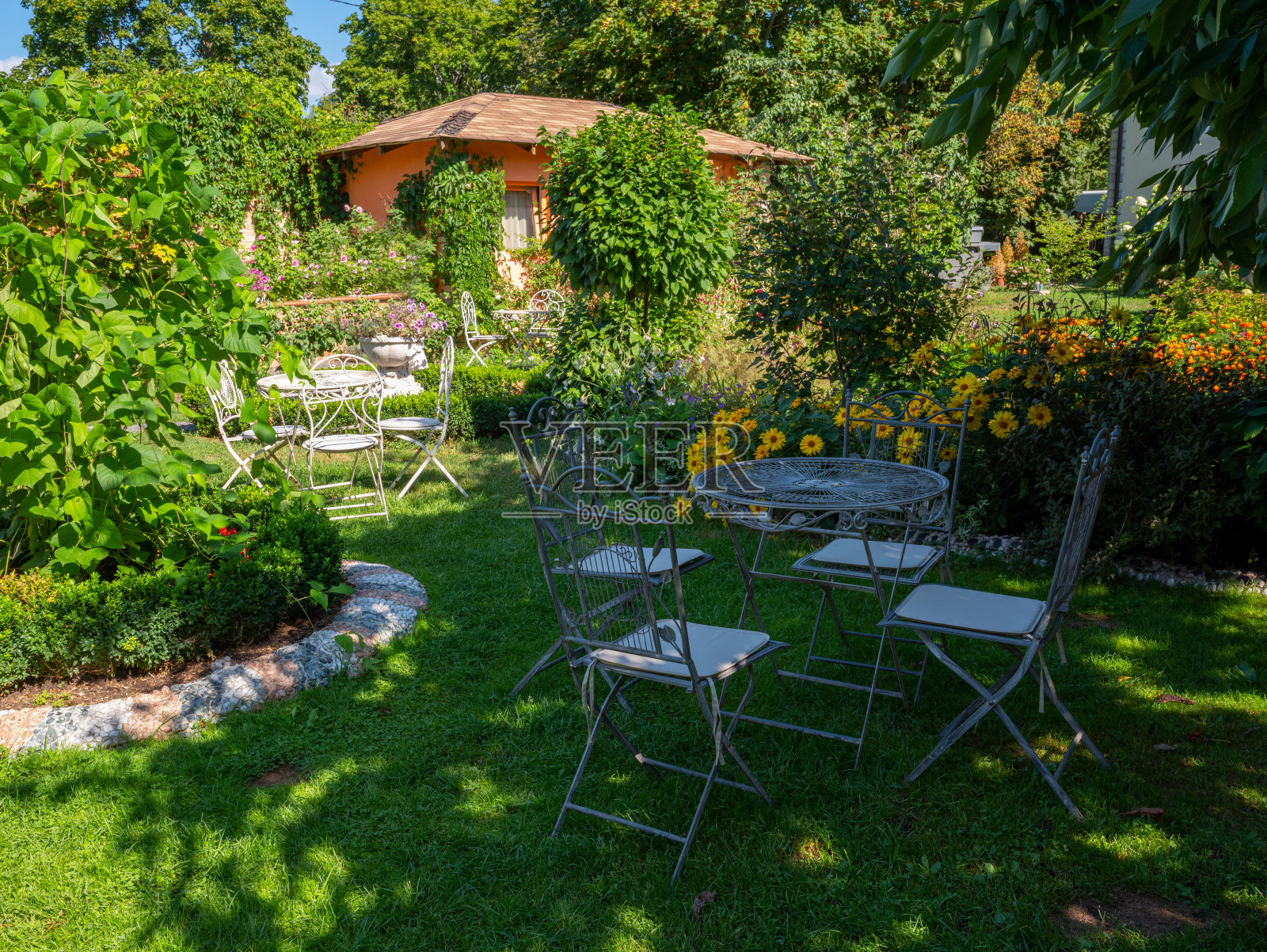 夏日花园中的桌椅。花瓶里有红花。阳光明媚的一天。照片摄影图片