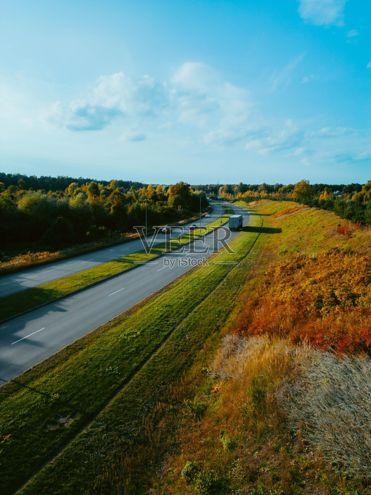 在晴朗的蓝天下，一辆卡车在晚上沿着高速公路行驶的俯视图照片摄影图片
