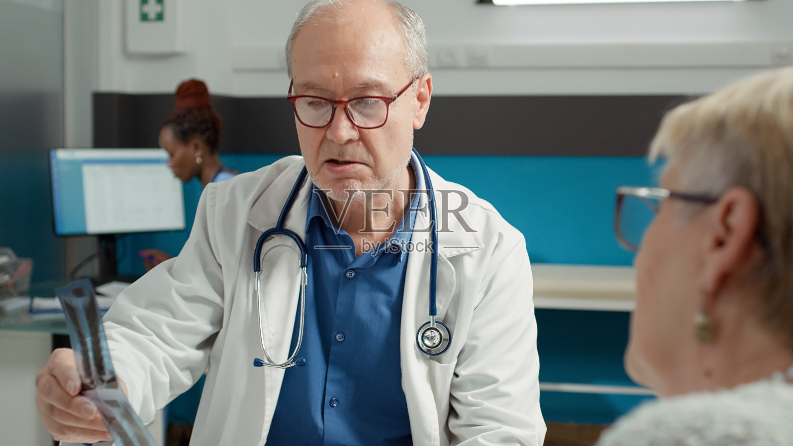 医生和老病人在检查时分析骨x光片照片摄影图片