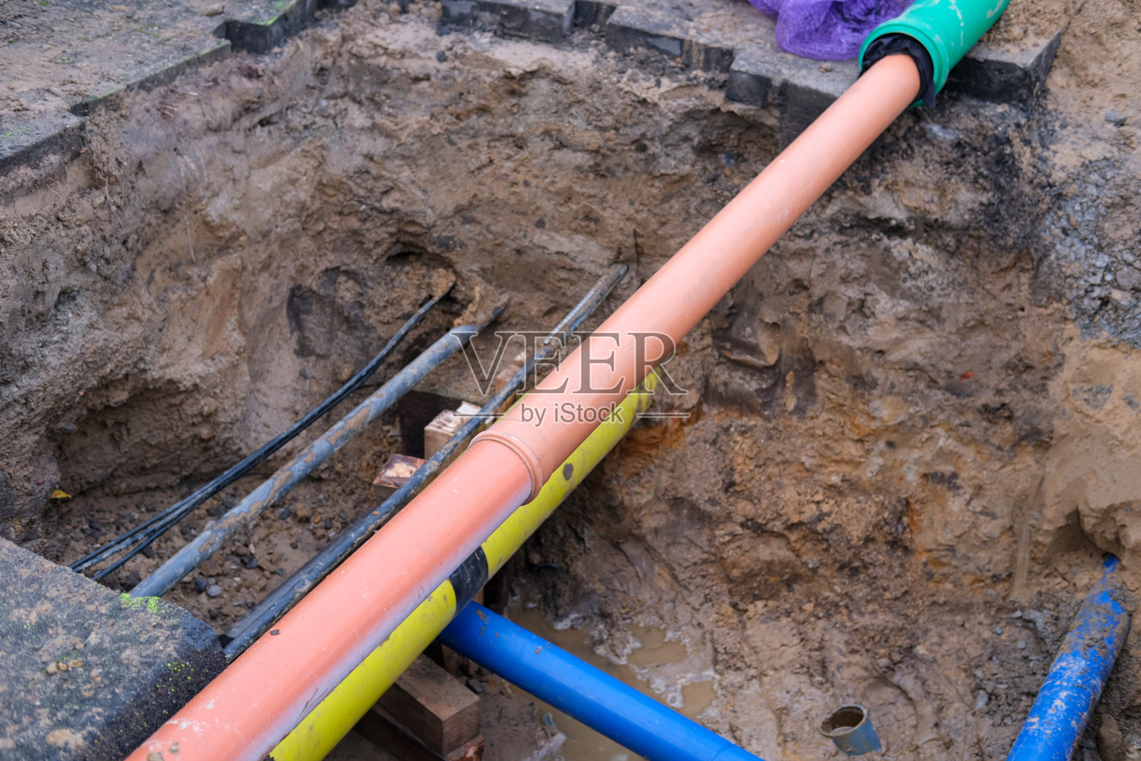 一个新铺设的下水道管道和其他公用设施连接和线路在一个挖掘坑的特写照片摄影图片